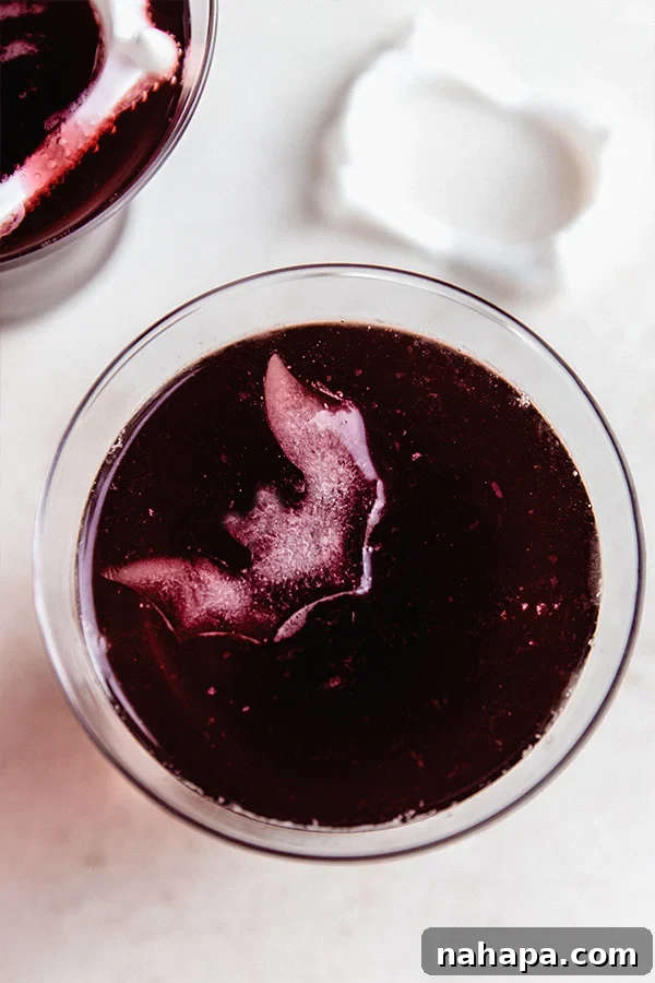 Nightwalker Nectar 4 A glass of Vampire Mocktail with spooky bat-shaped ice cubes floating, ready for a Halloween celebration.