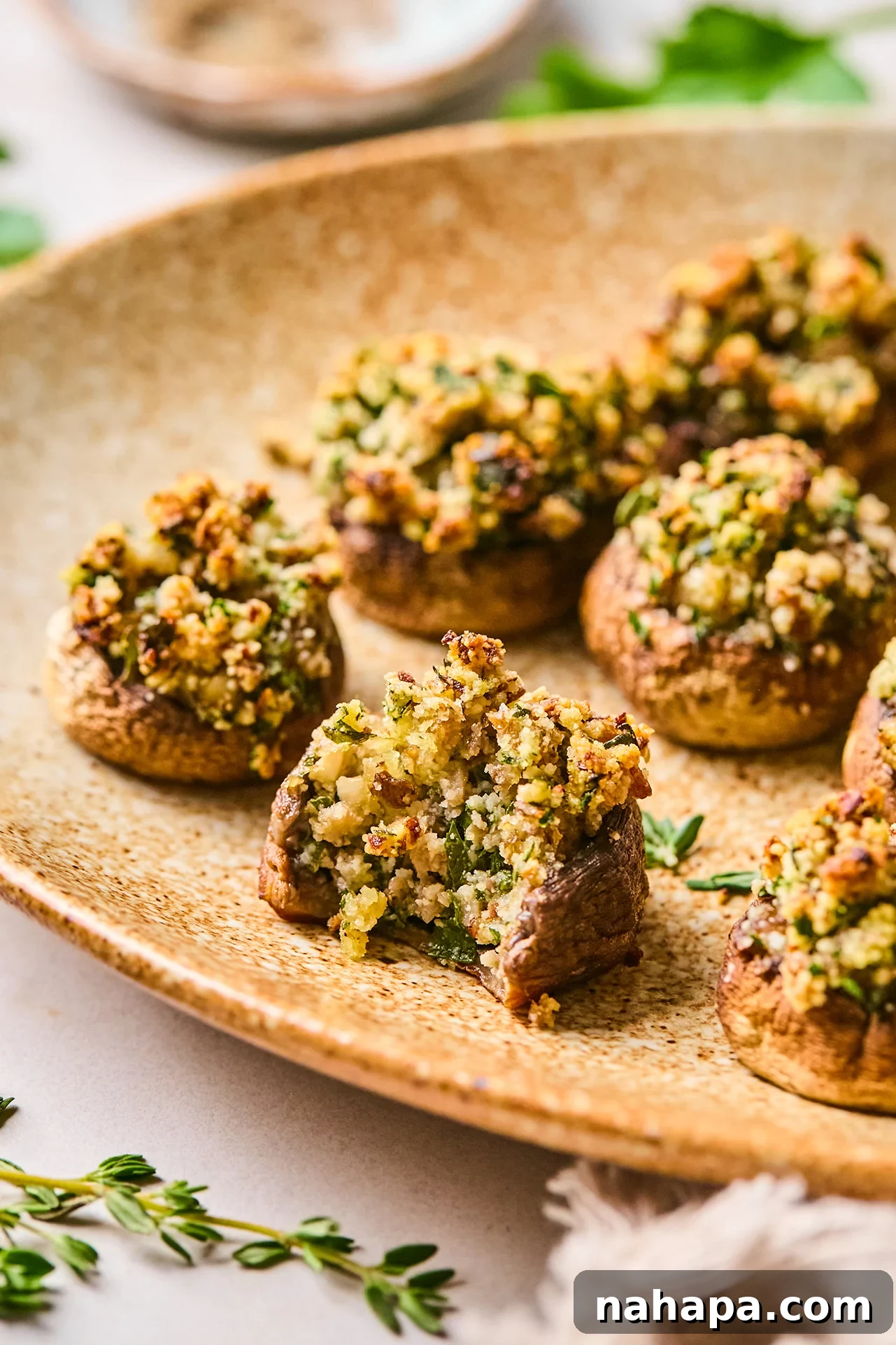 A stunning platter of golden-brown stuffed mushrooms, with one showcasing a perfect bite taken from its succulent cap.