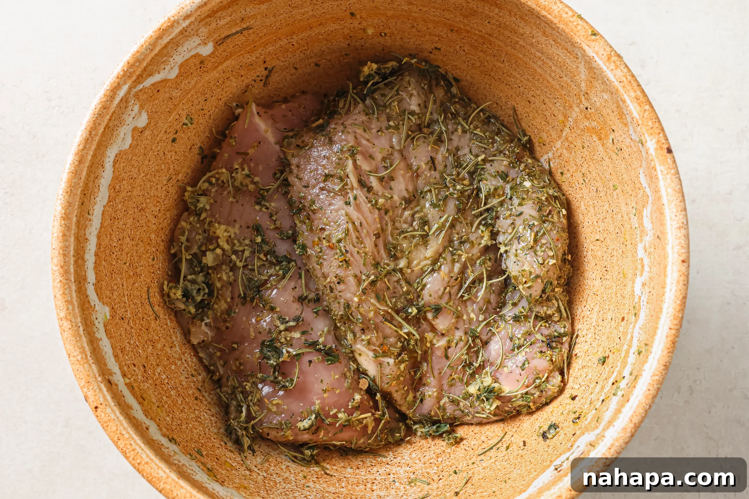 Turkey tenderloin marinating in a bowl.