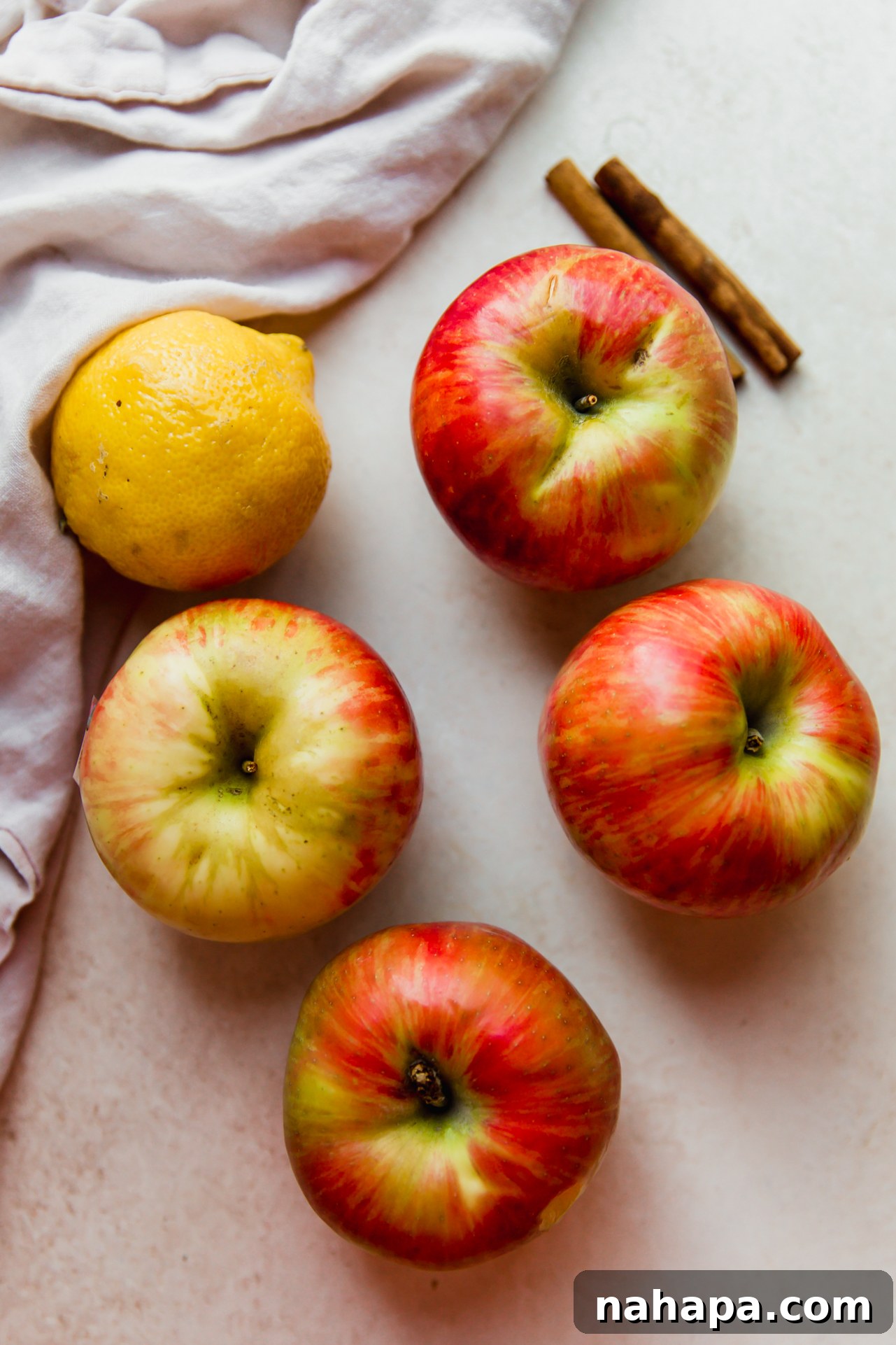 Crockpot Apple Comfort 3 Fresh ingredients for homemade apple sauce, including apples, lemon, cinnamon sticks, and coconut sugar.