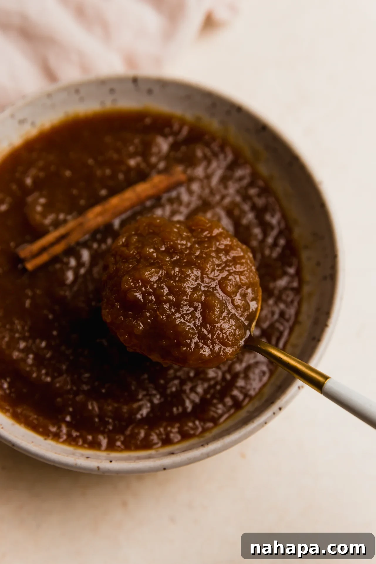 Crockpot Apple Comfort 5 Slow cooker apple sauce being scooped into a bowl with a spoon, showing its smooth, rich texture.