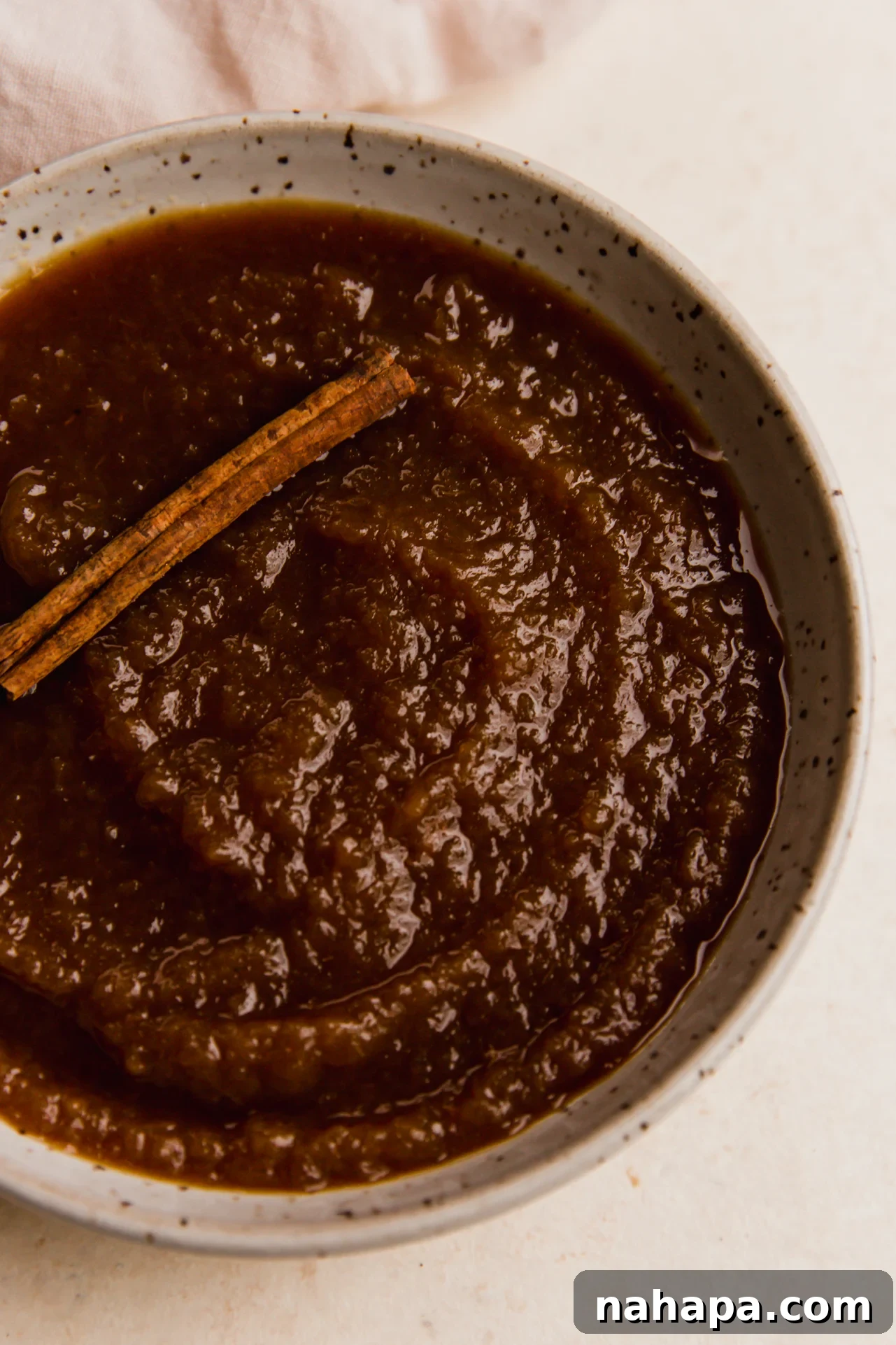 Slow cooker apple sauce topped with a cinnamon stick.