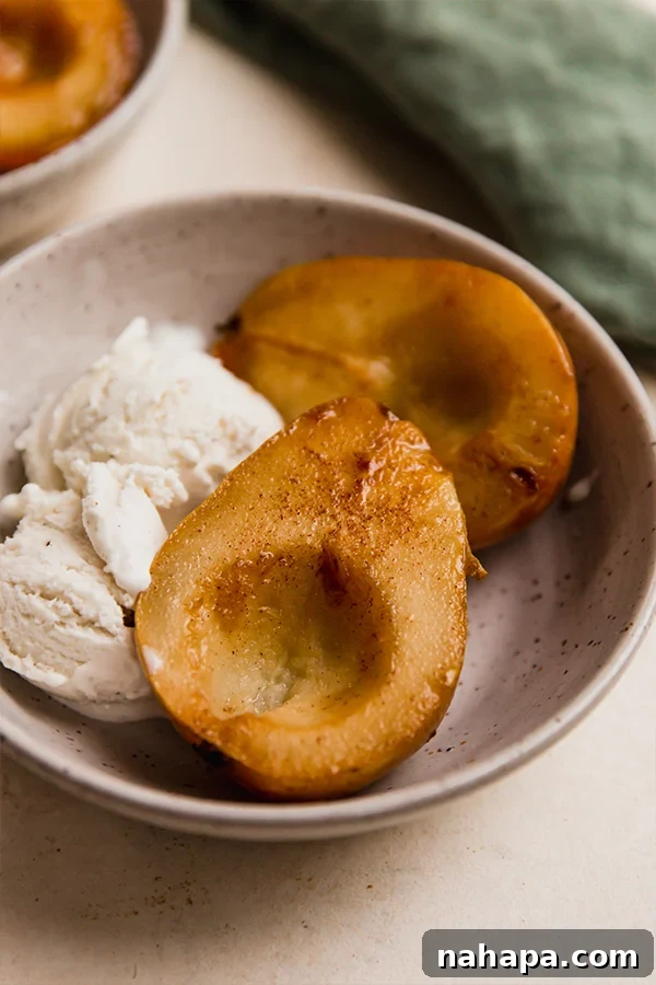 Perfectly Simple Baked Pears 5 A dish of four baked pear halves garnished with whipped cream and a sprinkle of cinnamon.