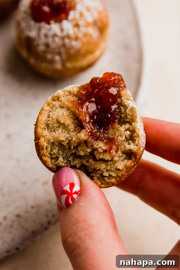 A person holding a delicious gluten-free jelly donut hole, showcasing its perfect texture and filling.