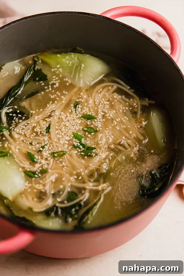 A pot of bok choy noodle soup simmering on the stove.
