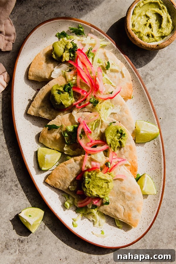 A plate of baked shredded beef tacos on a platter, garnished with fresh herbs and toppings.