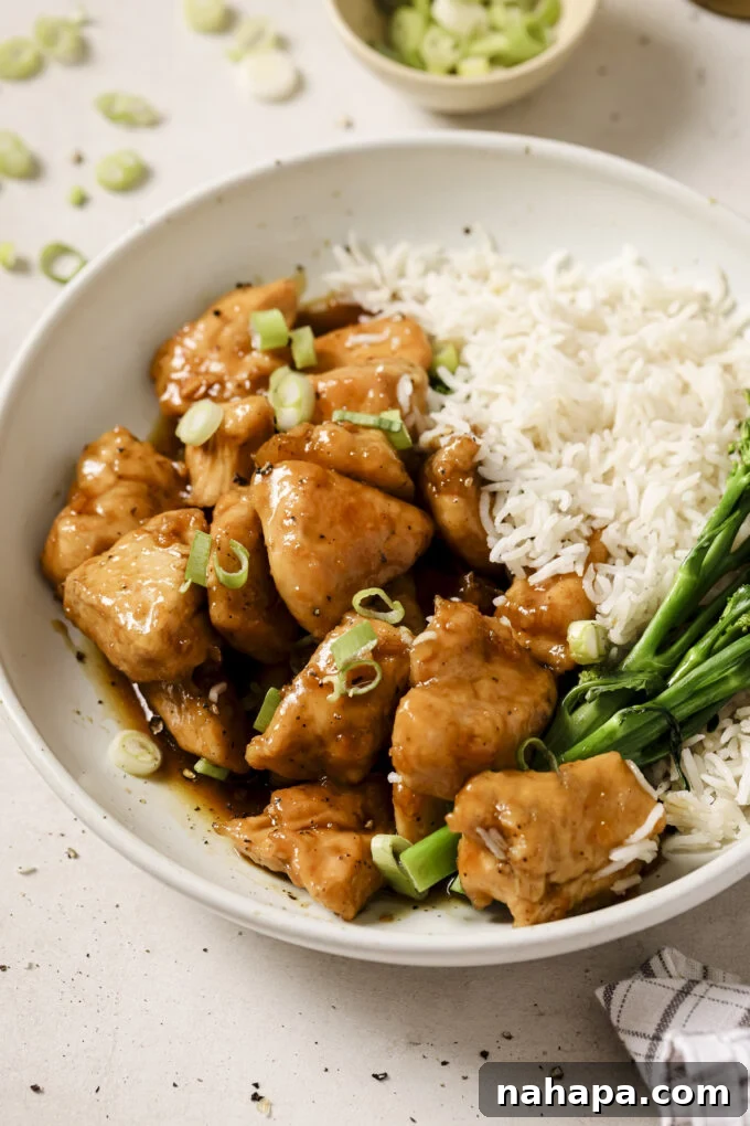 Honey butter chicken bites in a bowl with a side of rice and broccoli.
