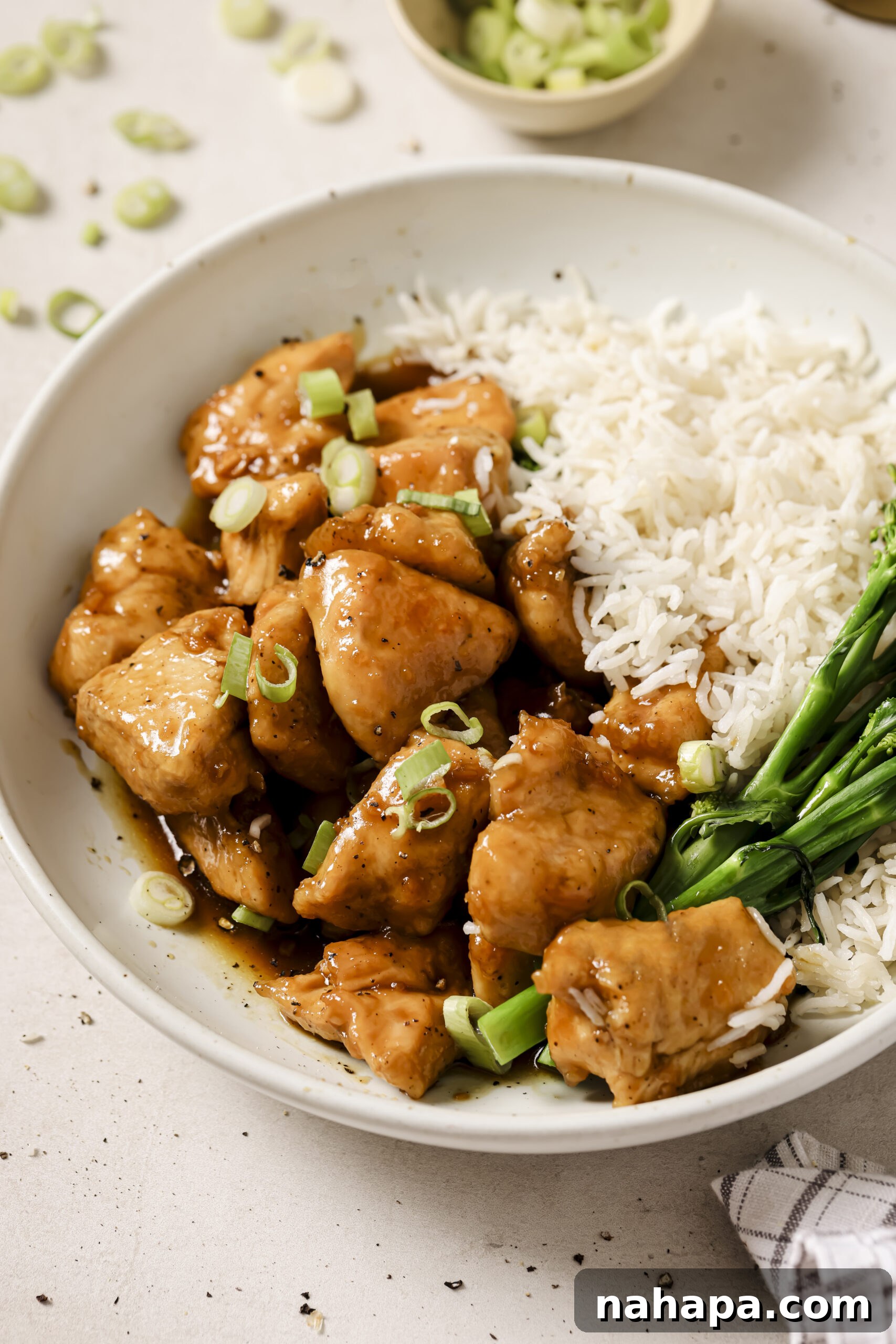 Honey butter chicken bites in a bowl with a side of rice and broccoli.