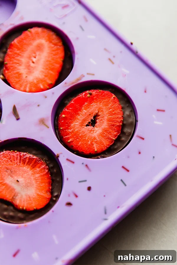Chocolate strawberry crunch bites perfectly set in silicone molds, ready to be chilled in the freezer.