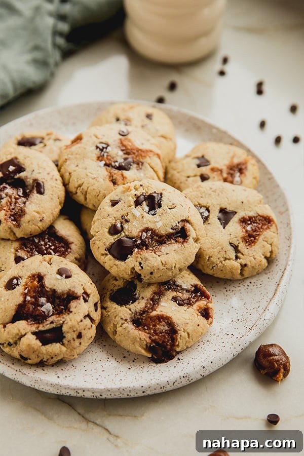A tantalizing plate of freshly baked gluten-free paleo chocolate chip caramel cookies, glistening with melted caramel and chocolate.