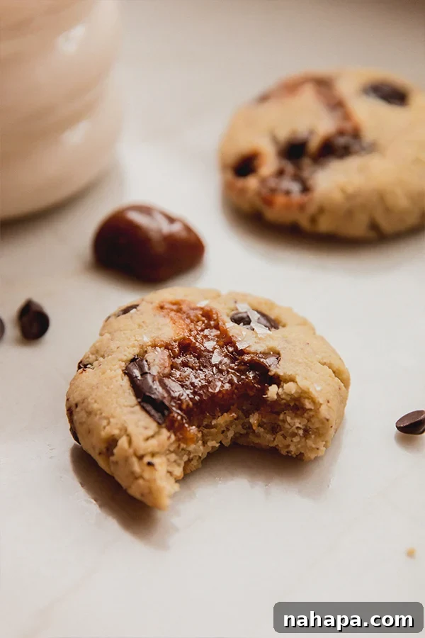 A delicious gluten-free paleo chocolate chip caramel cookie with a perfect bite taken out, revealing gooey center.