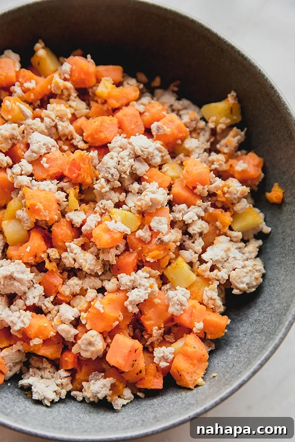 A close-up of a stovetop breakfast hash cooking in a skillet, with diced vegetables and ground meat.