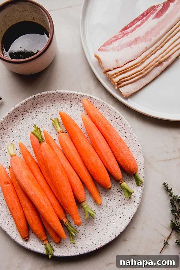 Close-up of bacon-wrapped carrots on a baking sheet before going into the oven, showing the glaze being brushed on.