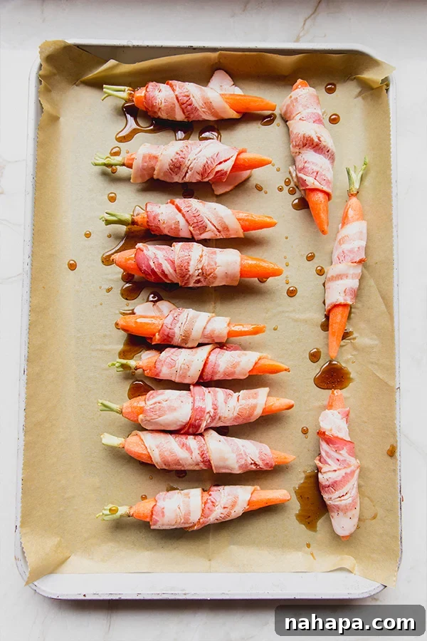 Bacon-wrapped carrots baking in the oven, showing early caramelization.
