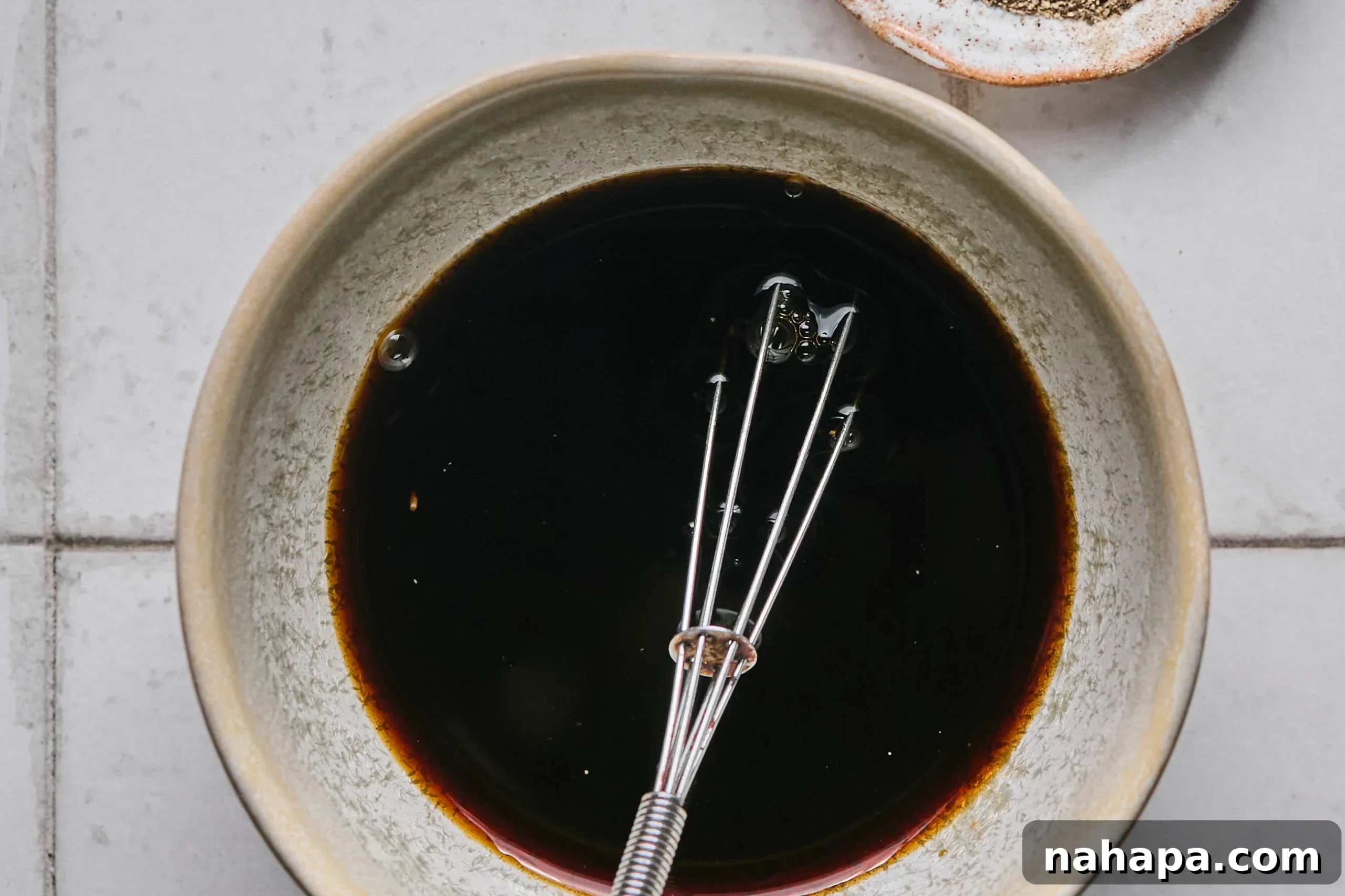 Pad Woon Sen Flavorful Gluten Free Glass Noodle Stir Fry 4 A small bowl containing the mixed Pad Woon Sen sauce, ready for use, with a whisk nearby.