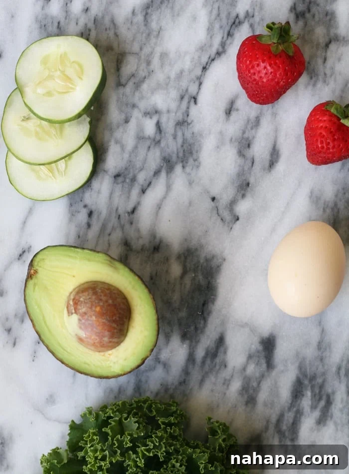 Fresh strawberries, cucumber, a hard-boiled egg, and avocado slices arranged on a clean kitchen countertop, highlighting natural, whole foods.
