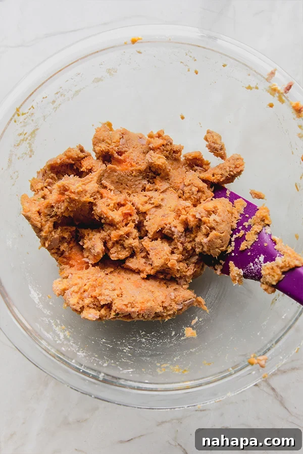 A glass bowl containing the mixed sweet potato tuna cake mixture, ready for forming.