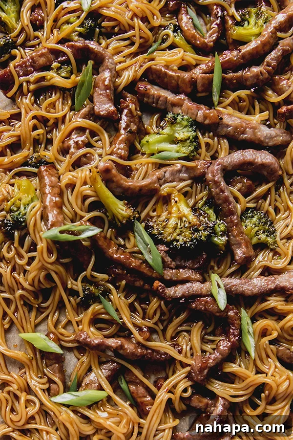 A sheet pan with cooked broccoli, sliced beef, and ramen noodles, ready to be tossed with sauce.