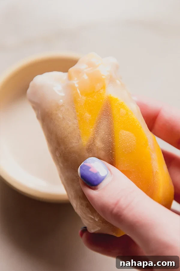 A mango sticky rice roll being held in a hand.