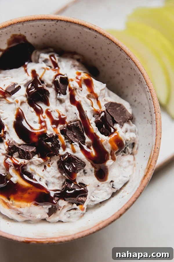 A close-up shot of a creamy, dairy-free Snickers salad dip in a bowl, showing the texture and caramel swirls, ready to be enjoyed.