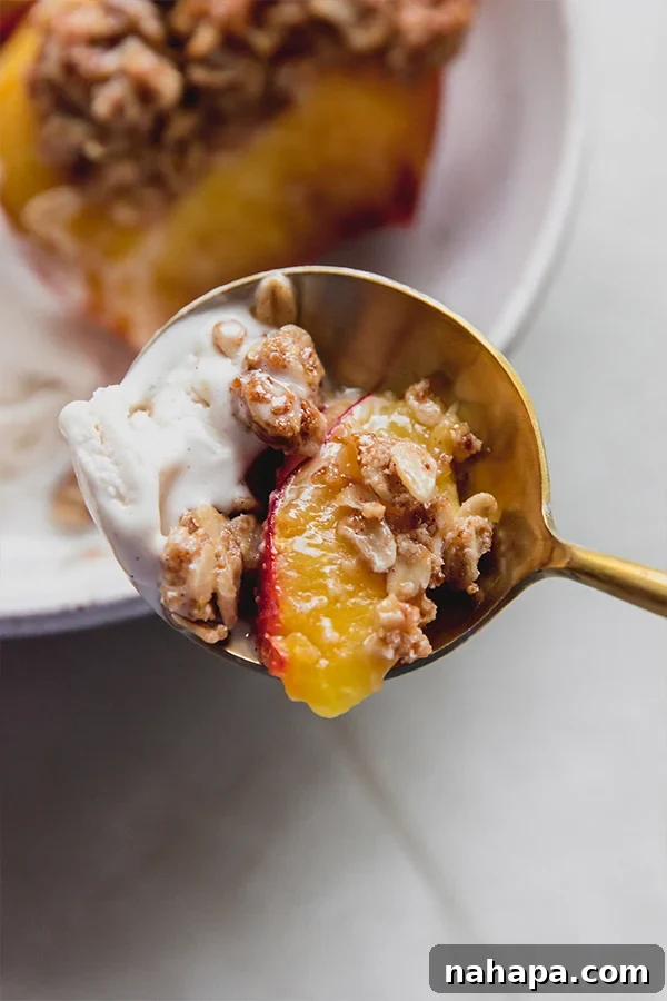 A bite of air fryer peach crisp and dairy free ice cream on a spoon.