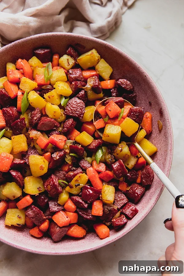 A serving bowl filled with healthier hot dog and veggie hash, accompanied by a serving spoon, ready to be enjoyed.