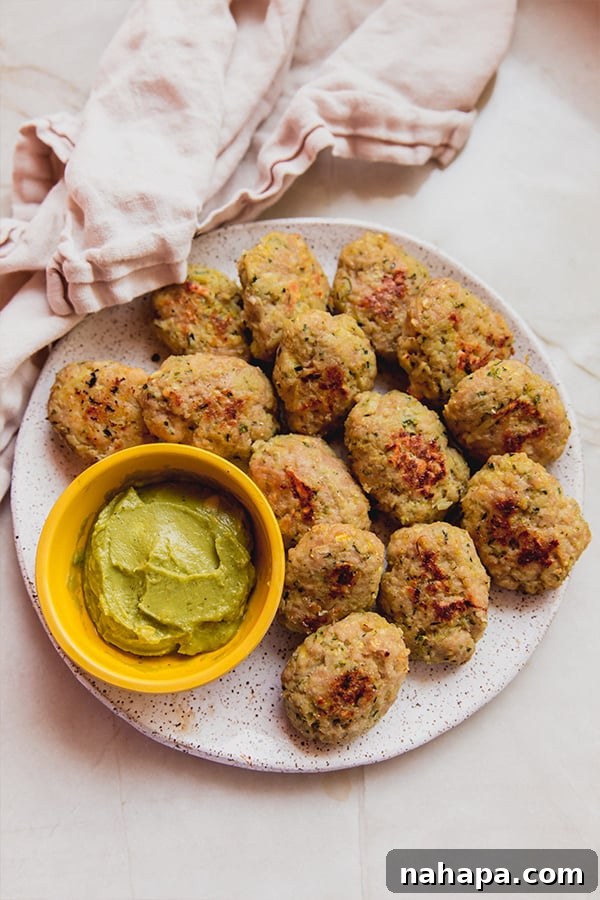A vibrant plate featuring golden zucchini chicken nuggets alongside various delicious dipping sauces.