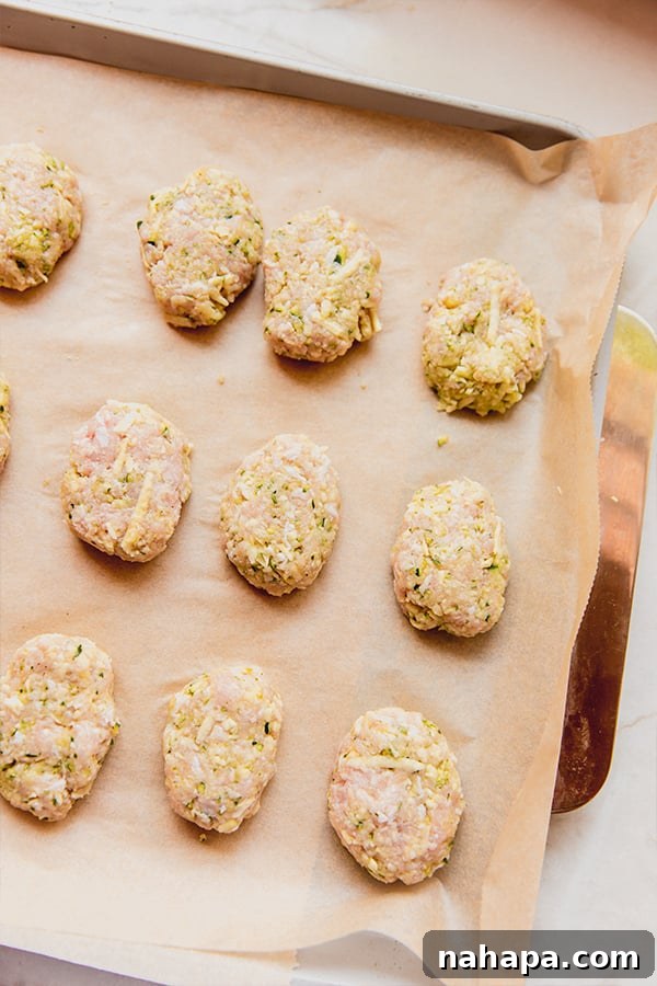 A baking sheet filled with perfectly shaped zucchini chicken nuggets, evenly spaced and ready to be baked to golden perfection.
