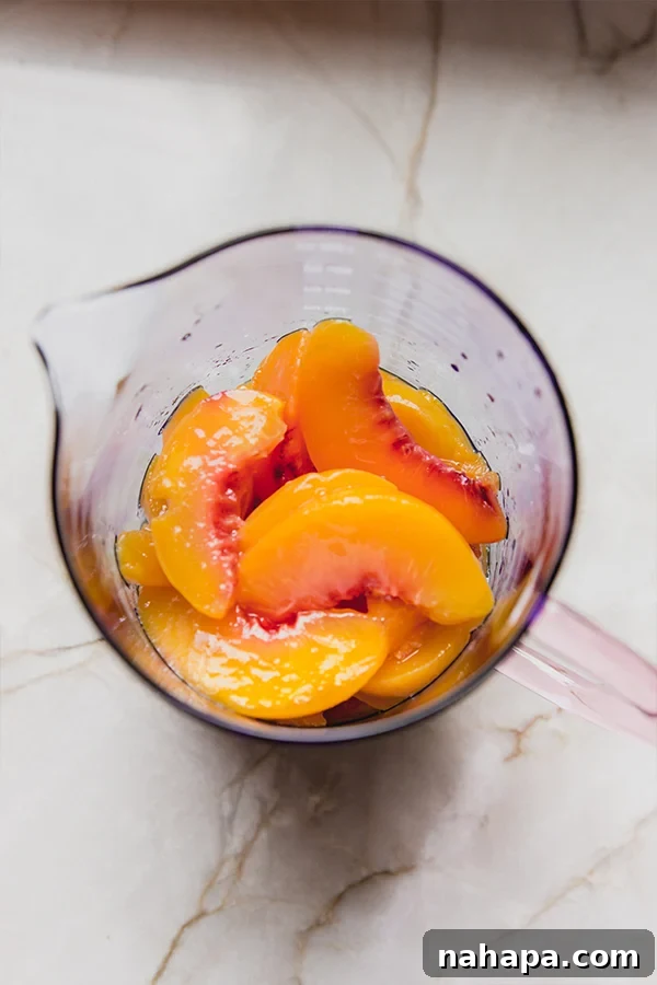 Peaches in a measuring cup, showcasing the fresh ingredients used in the peach ring gummy making process.