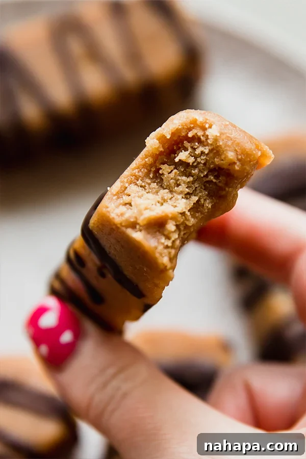 A single homemade cookie dough protein bar with a small bite taken out of it, revealing its dense, chewy interior and chocolate chips, resting on a white surface.