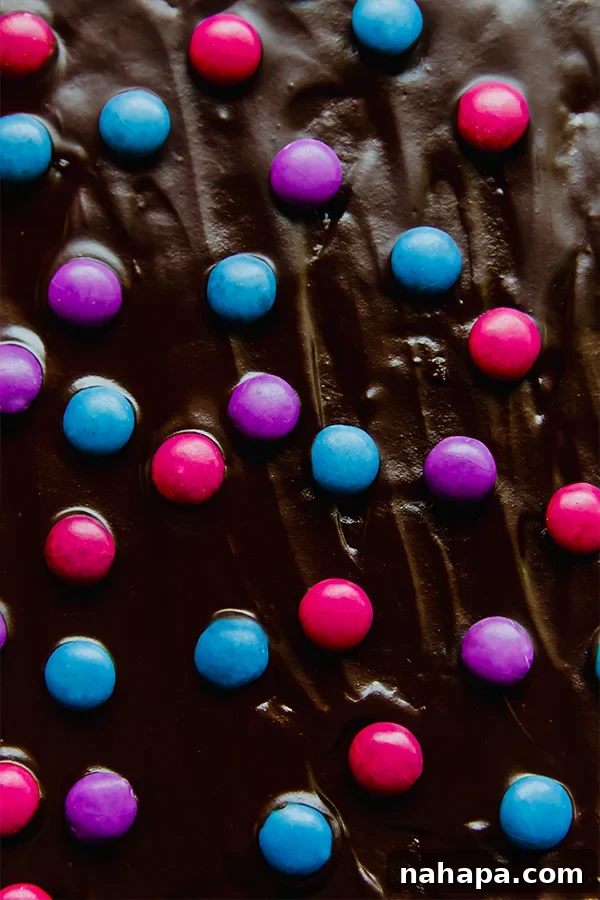 A close-up of a perfectly sliced Almond Flour Space Brownie with a rich ganache topping and colorful quinoa gems
