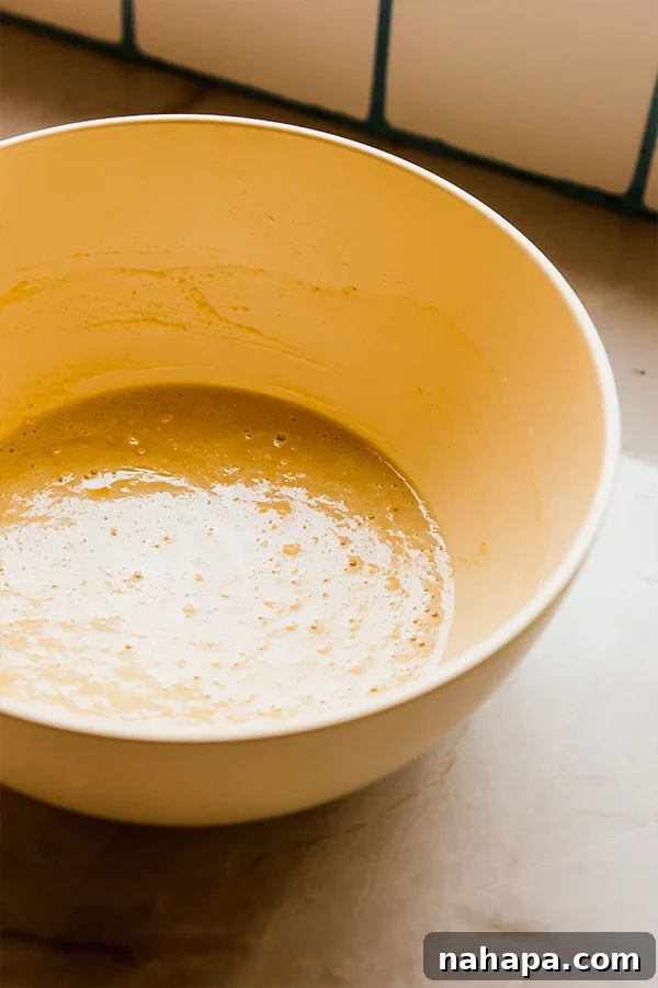 Socca: Effortless Golden Chickpea Flatbread 3 The smooth, light yellow batter for chickpea flatbread resting in a mixing bowl.