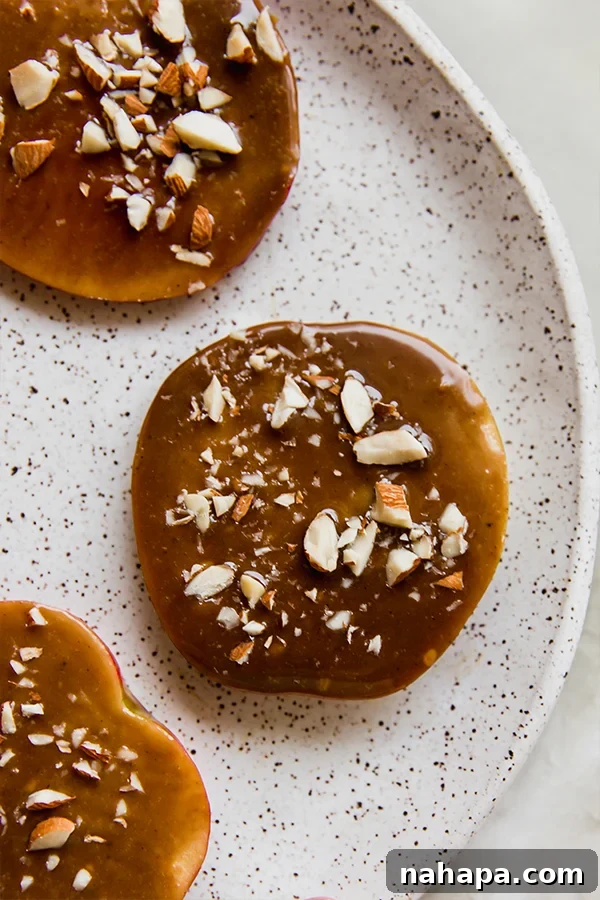 Caramel apple slices ready to be eaten on a plate, garnished with crushed nuts.