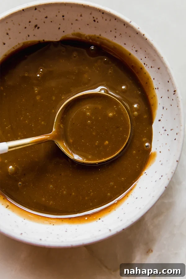A bowl of glossy coconut milk caramel, ready for apple slices, against a rustic background.
