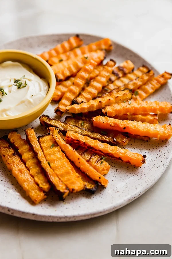 Air Fryer Crispy Zig Zag Butternut Squash Fries 2 A vibrant platter of golden brown butternut zig-zag fries, perfectly crisp and served with a creamy dipping sauce on the side.