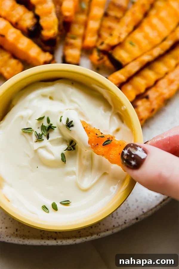 A vibrant platter of golden brown butternut zig-zag fries, perfectly crisp and served with a creamy dipping sauce on the side.
