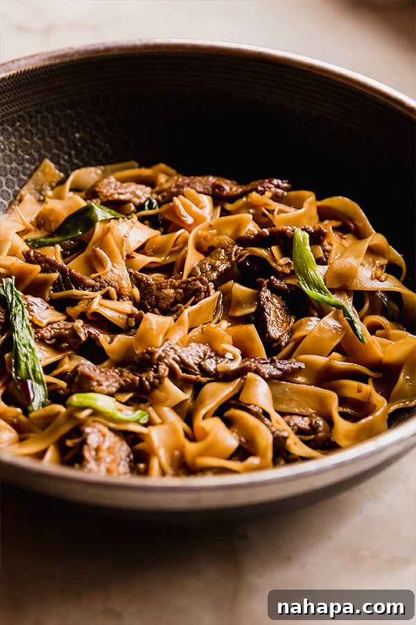 Wok-Kissed Gluten-Free Beef Chow Fun 5 A vibrant wok filled with freshly prepared gluten-free beef chow fun, with tender beef, wide noodles, and crisp vegetables glistening in the savory sauce.