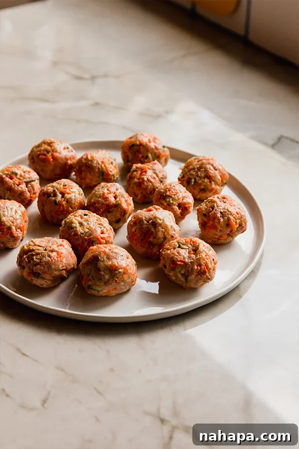 A plate neatly arranged with uncooked, uniformly sized hidden veggie meatballs, ready for searing.