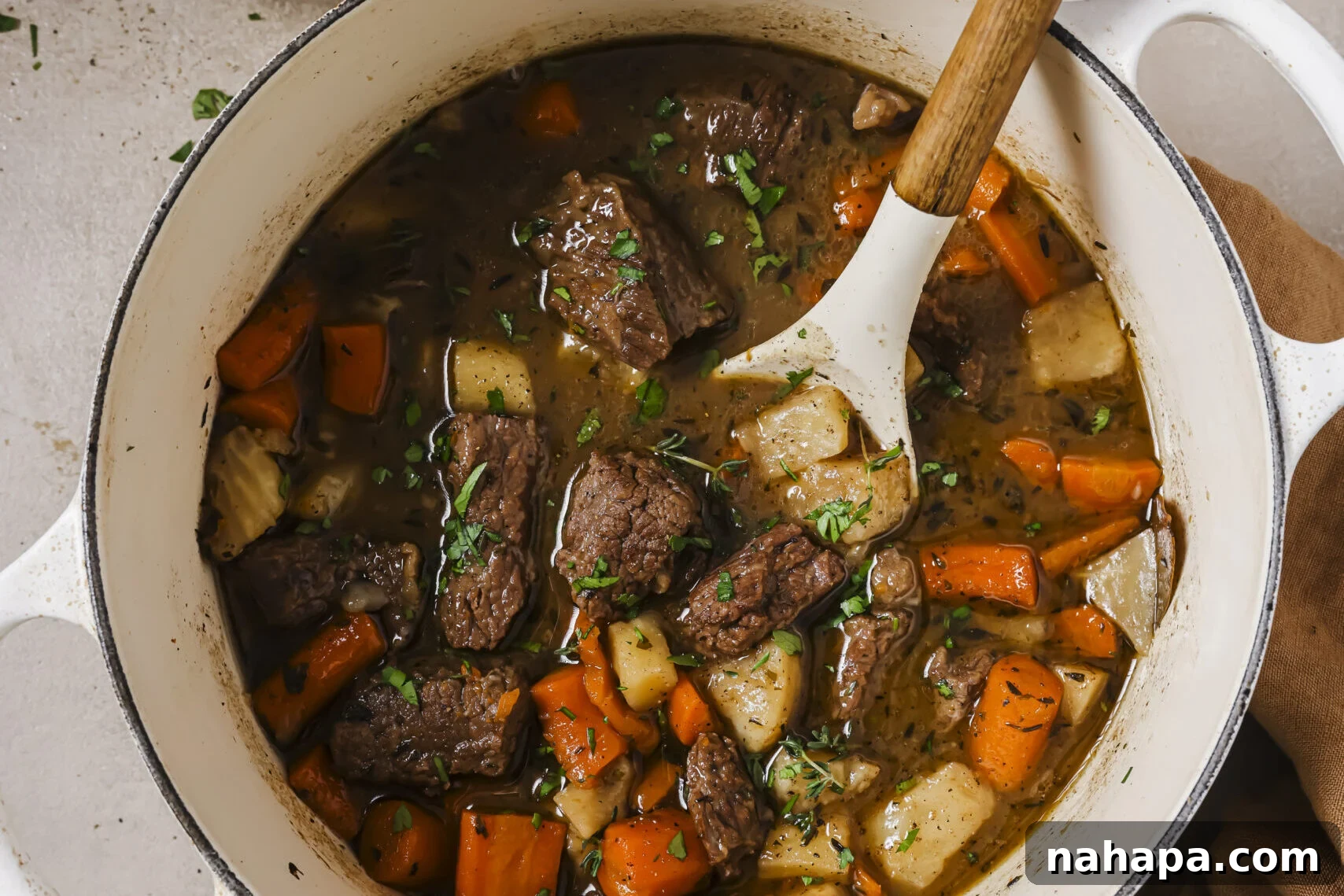 A close-up of Dutch oven beef stew simmering in the pot, garnished with fresh herbs.