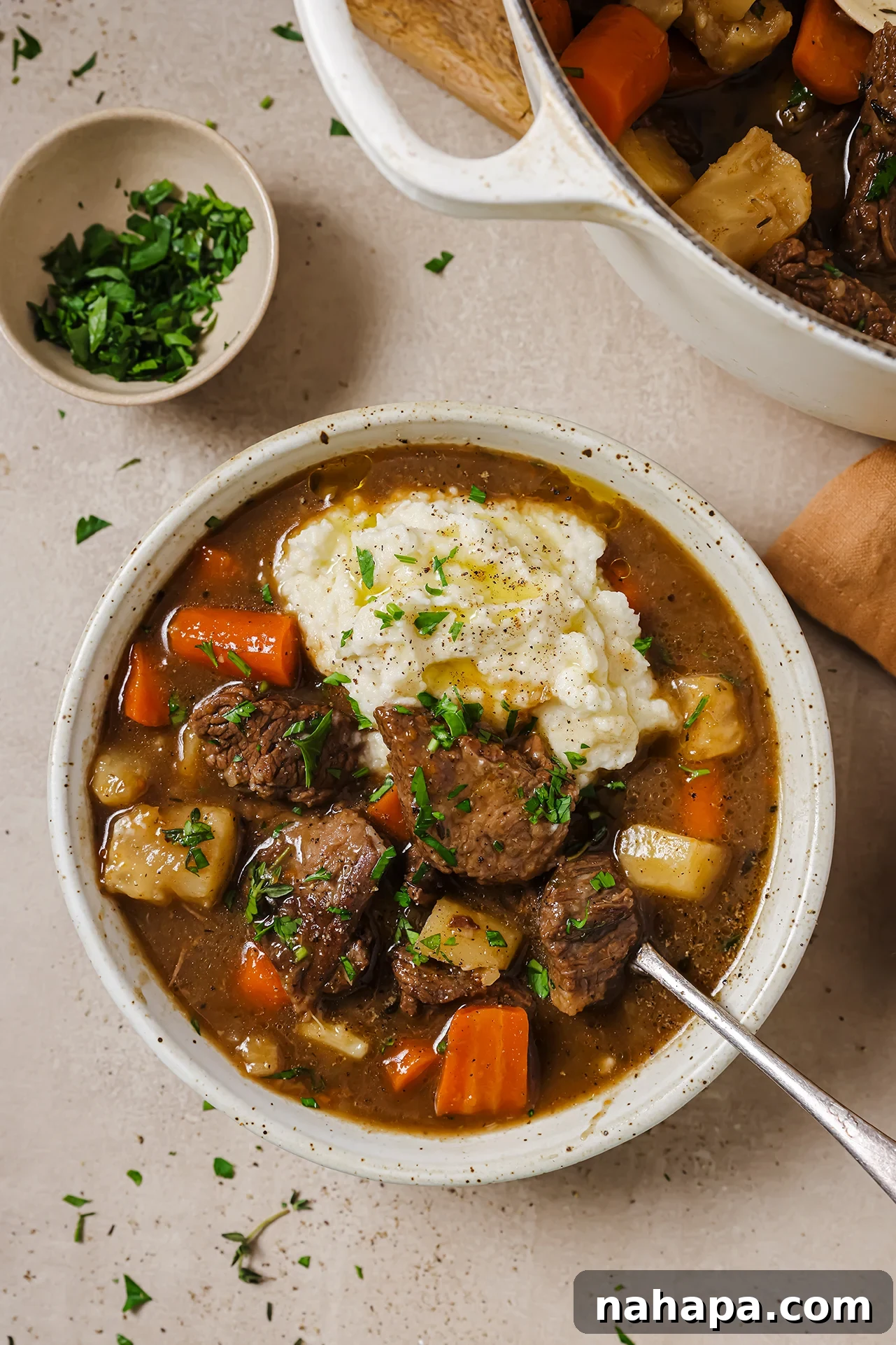 A bowl of Dutch oven beef stew served alongside a scoop of creamy mashed potatoes.