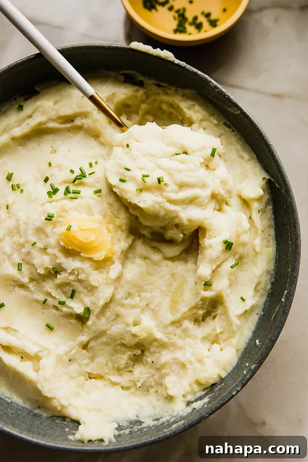 Creamy Instant Pot White Sweet Potato Mash 5 A serving bowl of creamy Instant Pot mashed white sweet potatoes, garnished with fresh chives, sitting elegantly on a kitchen counter.