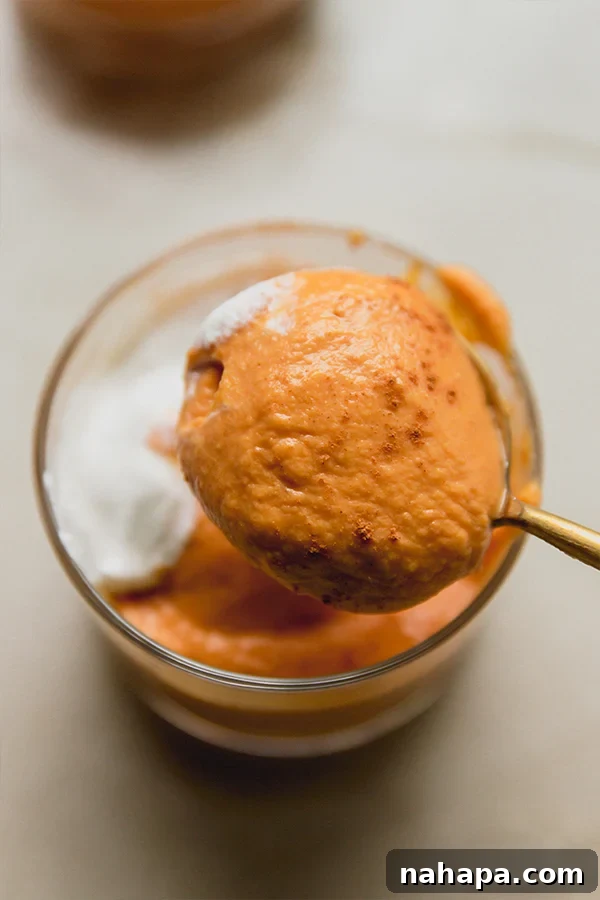 Velvety Plant-Based Pumpkin Treat Cups 4 A spoon lifting a spoonful of pumpkin cream out of a dessert cup.