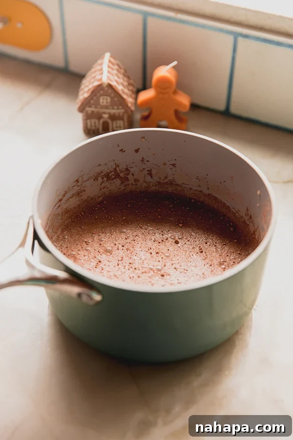 A pot of gingerbread hot cocoa ready to be poured into mugs, steaming and inviting.