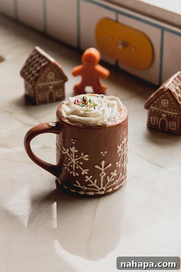 A mug of gingerbread hot cocoa with whipped cream and sprinkles.