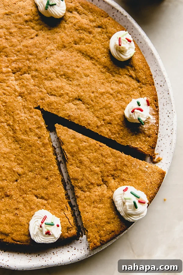 Three slices of Gluten-Free Gingerbread Cookie Cake with white frosting and festive sprinkles on a white plate.