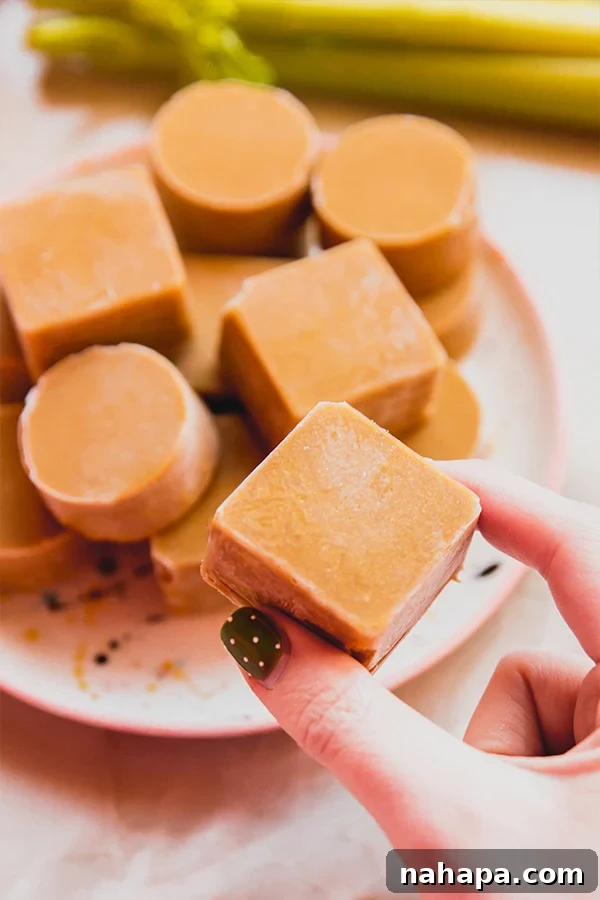 Pure Beef Flavor Cubes: Made from Scratch 5 A hand reaching for a homemade beef bouillon cube from a perfectly arranged stack on a kitchen counter, emphasizing easy access and convenience.