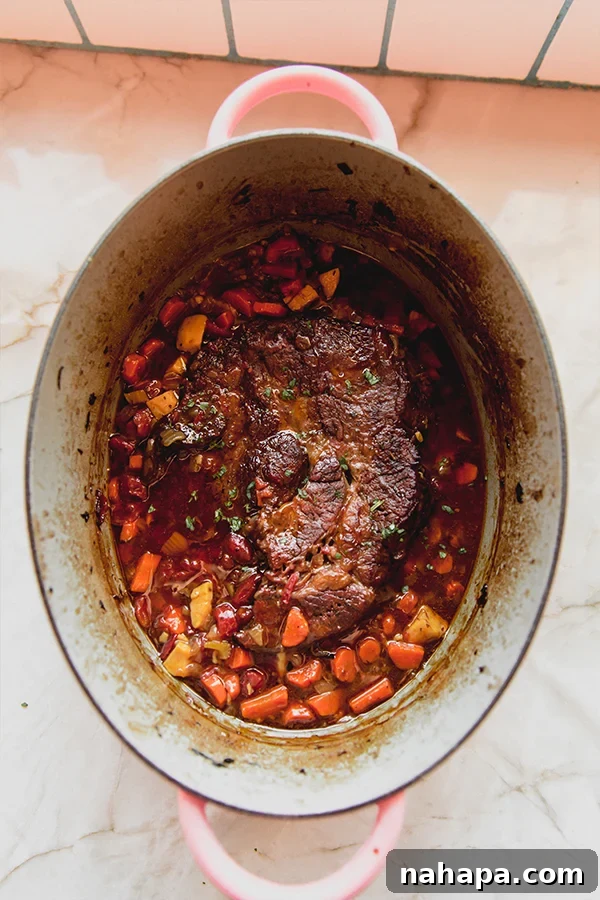 A beautifully cooked Italian pot roast in a Dutch oven with ladle, ready to be served.