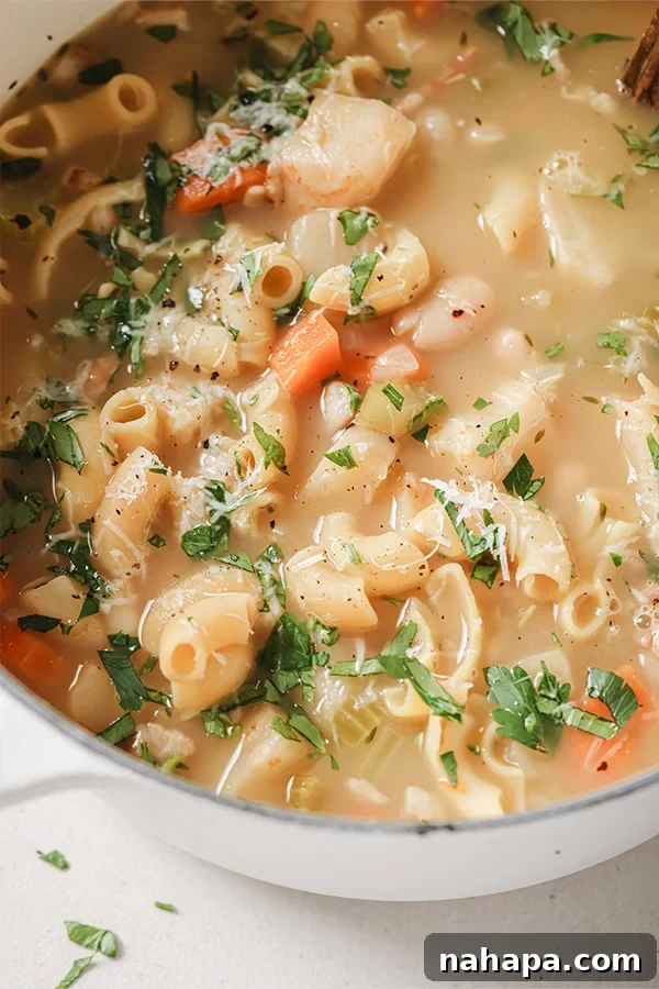 A steaming pot of creamy white pasta fagioli soup, ready to be served and enjoyed.