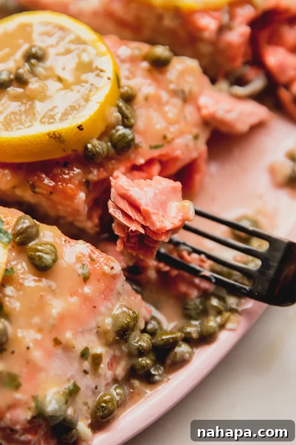 Flavorful Salmon Piccata Without Gluten or Dairy 4 A fork taking a bite of salmon piccata off the serving platter.