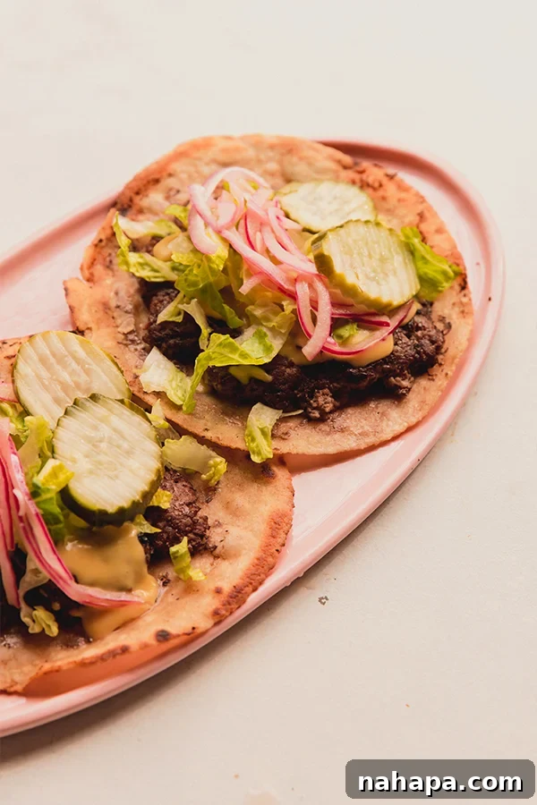 A plate filled with two smash burger tacos with all the toppings, ready to be enjoyed.
